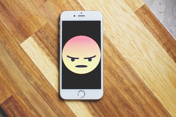 An iPhone with an angry face emoji, feeling undervalued